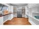 Bright pantry with custom shelves, stainless steel refrigerator, countertop, and wood grain flooring at 915 Bayshore Dr, Tarpon Springs, FL 34689