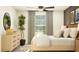Serene bedroom with a natural wood dresser, lush indoor plant, and modern decor at 10274 Gentle Rain Dr, Land O Lakes, FL 34638