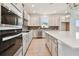 Modern kitchen showcasing stainless steel appliances, tile backsplash, white cabinets, and quartz countertop island at 11834 Mile Marsh Dr, Riverview, FL 33569
