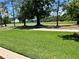Beautifully landscaped backyard overlooking the golf course with mature trees and green grass at 1201 Ventana Dr, Sun City Center, FL 33573