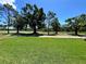 Serene backyard view overlooking the golf course with mature trees and lush green grass at 1201 Ventana Dr, Sun City Center, FL 33573
