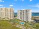 Aerial view of beachfront condos with a pool, tennis courts, and lush landscaping at 1230 Gulf Blvd # 508, Clearwater Beach, FL 33767