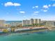Aerial view of a coastal city with high-rise condos, the ocean, and waterfront commercial buildings under a blue sky at 1230 Gulf Blvd # 508, Clearwater Beach, FL 33767