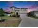 Charming two-story home featuring a two-car garage, beautiful landscaping, and inviting curb appeal at sunset at 13234 Great Plains Dr, Riverview, FL 33579