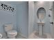 Stylish powder room with a pedestal sink, oval mirror, and a decorative leaf design on light blue walls at 13234 Great Plains Dr, Riverview, FL 33579