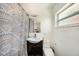 This bathroom includes a single sink vanity, toilet, shower with patterned curtain, and a window at 1557 Robinson N Dr, St Petersburg, FL 33710