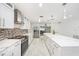 Modern kitchen featuring white cabinets, stainless appliances, backsplash, and a marble island with pendant lighting at 1557 Robinson N Dr, St Petersburg, FL 33710