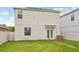Spacious backyard with a green lawn, white fence, and the home's exterior featuring solar panels at 17331 White Mangrove Dr, Wimauma, FL 33598