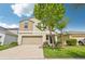 Two-story home featuring a two-car garage, neutral exterior paint, manicured lawn, and blue skies at 17331 White Mangrove Dr, Wimauma, FL 33598