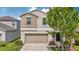 Charming two-story home featuring tan exterior, a two-car garage and landscaped front lawn at 17331 White Mangrove Dr, Wimauma, FL 33598
