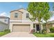 Charming two-story home featuring tan exterior, a two-car garage and landscaped front lawn at 17331 White Mangrove Dr, Wimauma, FL 33598