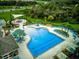 Aerial view showcases a large community pool with lounge chairs and a splash pad nestled within lush landscaping at 17331 White Mangrove Dr, Wimauma, FL 33598