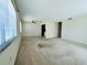 Spacious living room area featuring neutral carpet, a ceiling fan, and multiple windows at 203 Rickenbacker Dr, Sun City Center, FL 33573