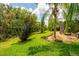 Beautifully landscaped backyard with lush green grass, tropical trees and a screened-in lanai offering privacy at 211 Royal Bonnet Dr, Apollo Beach, FL 33572