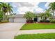 Inviting single-story home features a well-manicured lawn, mature palm trees, and a three-car garage at 211 Royal Bonnet Dr, Apollo Beach, FL 33572