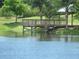 Wooden pier on a calm community pond, surrounded by green grass and mature trees, offering a peaceful outdoor space at 211 Royal Bonnet Dr, Apollo Beach, FL 33572