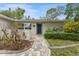 Inviting entryway with brick walkway and manicured garden beds leading to a painted front door at 25 Harbor Oaks Cir, Safety Harbor, FL 34695