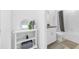 All-white bathroom with vanity and mirror, shelf with decorations, and combined shower and tub at 36454 Flats St, Zephyrhills, FL 33541