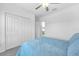 Light-filled bedroom showcasing a blue bedspread, large closet doors, and a peek into the en-suite bathroom at 36454 Flats St, Zephyrhills, FL 33541