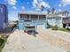 Two-story waterfront home with a two-car garage, boat on trailer, and a mix of paved and gravel driveway at 4039 Casa Ct, Hernando Beach, FL 34607