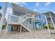 Exterior view of a stilt home with white stairs and a porch, showcasing its coastal architecture at 4039 Casa Ct, Hernando Beach, FL 34607