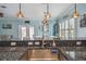 Kitchen island with stainless steel sink, granite countertop, and unique pendant lighting at 4039 Casa Ct, Hernando Beach, FL 34607