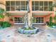 Elegant condo building entrance with a beautiful dolphin statue, tile walkway, and lush tropical plants at 4516 Seagull Dr # 903, New Port Richey, FL 34652