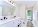 This bright bathroom offers a double sink vanity with a large mirror and a walk-out to the backyard at 5114 Whispering Leaf Trl, Valrico, FL 33596