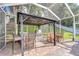 The outdoor kitchen features a grill, bar seating, and dining table at 5114 Whispering Leaf Trl, Valrico, FL 33596