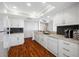 A condo kitchen boasts granite counters, wood floors, white cabinets, stainless steel sink, and recessed lighting at 7600 Bayshore Dr # 1206, Treasure Island, FL 33706