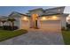 Elegant home exterior featuring a three-car garage, manicured lawn, and a brick-paved driveway at 8346 Ivy Stark Boulevard, Wesley Chapel, FL 33545