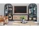 Living room with decorative display cases and console with TV above a small cabinet at 8346 Ivy Stark Boulevard, Wesley Chapel, FL 33545