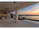 Serene covered patio view of lake and pool with outdoor kitchen at sunset at 8346 Ivy Stark Boulevard, Wesley Chapel, FL 33545