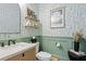 Stylish powder room featuring decorative wallpaper, stylish mirror, and green accent wall at 8346 Ivy Stark Boulevard, Wesley Chapel, FL 33545