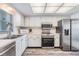 Charming kitchen with stainless steel appliances, white cabinetry, and sleek laminate flooring at 9 Forbes Pl # 205, Dunedin, FL 34698