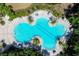 Aerial view of a clover-shaped community pool surrounded by lounge chairs and lush landscaping at 9567 Sandy Bluffs Cir, Parrish, FL 34219