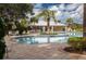 Outdoor swimming pool with lounge chairs, tables and umbrellas surrounded by tropical landscaping at 9567 Sandy Bluffs Cir, Parrish, FL 34219