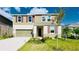 Two-story home with neutral siding, shuttered windows, two-car garage, and landscaped front yard on a sunny day at 9567 Sandy Bluffs Cir, Parrish, FL 34219