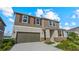 Two-story home with neutral siding and shutters, two-car garage, and landscaping on a sunny day at 9567 Sandy Bluffs Cir, Parrish, FL 34219