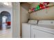 Bright laundry area with washer and dryer and shelving for storage; the living room is adjacent at 9814 Ashburn Lake Dr, Tampa, FL 33610