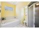 Bathroom with yellow walls featuring white cabinets, a sink, toilet, and bathtub with shower at 10021 Elgin Blvd, Spring Hill, FL 34608