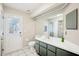Bright bathroom featuring a white sink, toilet, and door to outside, with gray and white tile flooring at 10021 Elgin Blvd, Spring Hill, FL 34608