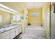 Bathroom with yellow walls featuring white cabinets, a sink, toilet, and bathtub with shower at 10021 Elgin Blvd, Spring Hill, FL 34608