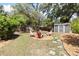 Backyard with chairs in a gravel area and a shed in the background surrounded by green grass at 1222 E Powhatan Ave, Tampa, FL 33604