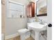 Updated bathroom featuring a pedestal sink, toilet, window and cherry-wood cabinet at 1222 E Powhatan Ave, Tampa, FL 33604
