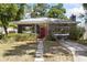 Charming single-story home with a well-manicured front yard and a welcoming red front door at 1222 E Powhatan Ave, Tampa, FL 33604