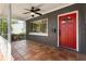 The front porch of the home features a ceiling fan and a vibrant red front door at 1222 E Powhatan Ave, Tampa, FL 33604