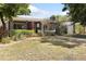 A single-story home with a red front door, gray siding, a well-kept lawn and mature shrubbery at 1222 E Powhatan Ave, Tampa, FL 33604