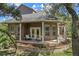 Covered back porch featuring rocking chairs, a brick accent wall, and views of the landscaped yard at 15053 Peace Blvd, Spring Hill, FL 34610