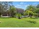 Lush backyard with green grass, mature landscaping, and a charming two-story home in the background at 15053 Peace Blvd, Spring Hill, FL 34610